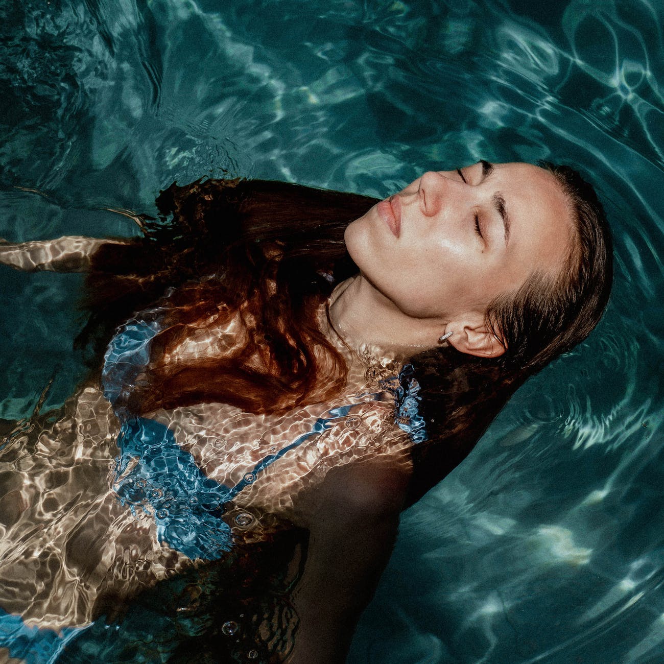 woman wearing blue bikini top swimming in water