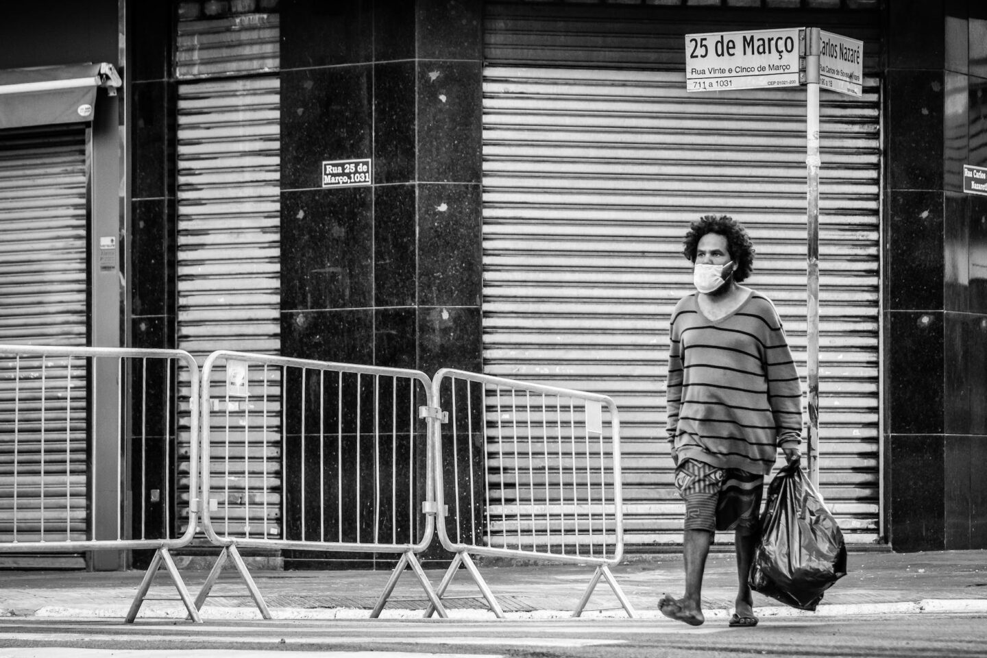 unrecognizable black man in mask walking on street with bag